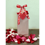 Gift bag with red heart ribbon and scattered rose petals