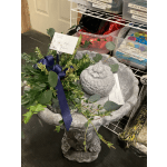 Greenery wreath around a gray bird bath with a stone bird figure