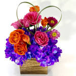 Pink and orange roses with purple flowers in a wooden basket