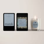 Three packaged candles, one lit in a clear glass holder