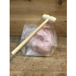 Clear plastic gift box with a pink ribbon and wooden mallet on a wood surface