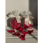 Two clear gift bags filled with red rose petals and tied with white ribbons