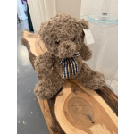 Brown teddy bear with a plaid ribbon sitting on a wooden bench