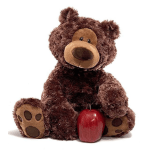 Brown plush teddy bear sitting with an apple-shaped red candle by its feet