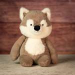 Plush wolf toy sitting against a wood backdrop