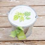 Metal herb pail with a green ribbon and plant illustration on the lid