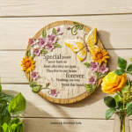 Round wooden memorial plaque with flowers and a butterfly