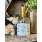 Perfume bottle beside cotton stems in a planter