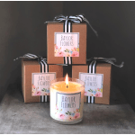 Lit candle in a glass jar with three ribbon-tied gift boxes behind it