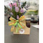 Gift caddy with pastel tulip bouquet, plaid bow, and iced tea cup on a table
