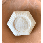 White decorative candle with a beehive relief in a terracotta bowl