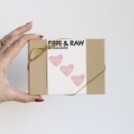 Gift box with heart graphics and gold ribbon held in a hand