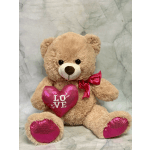 Teddy bear holding a pink heart with a red bow
