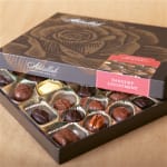 Open box of assorted chocolates with patterned lid partially covering the tray.