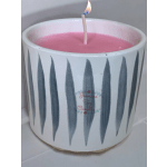 Pink candle in a white ceramic holder with a lit wick