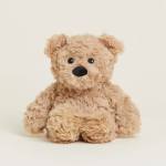 Small tan plush teddy bear sitting upright on a light background