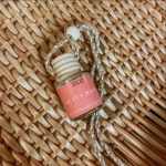 Small hanging glass bottle with a pink label and braided cord
