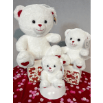 Three white teddy bears with red heart details on a heart-patterned display.