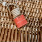 Small perfume bottle with a coral label hanging on a woven surface