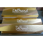 Stacked gold boxes of DeBrand fine chocolates tied with ribbon