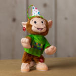 Plush monkey wearing a birthday hat and green shirt