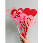 Hand holding several pink and red heart-shaped picks