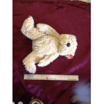Plush teddy bear lying on a burgundy fabric background