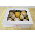 Box of white chocolate-covered strawberries decorated with yellow drizzle