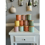 Stacked scented candles in pastel jars on a white table