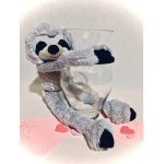 Gray sloth plush toy hugging a clear glass vase on pink heart doilies