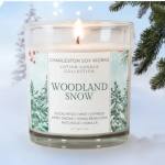Lit glass candle labeled Woodland Snow