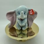 Plush elephant toy with a Ty heart tag on a gold pedestal