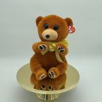 Brown teddy bear with a yellow ribbon sitting on a mirrored stand