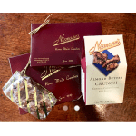 Assorted boxed candies and almond butter crunch package on a wooden surface