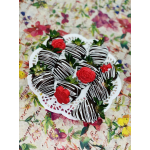 Chocolate-covered strawberries with white drizzle and red flower decorations on a doily tray