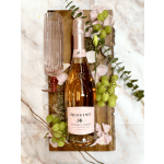 Bottle of rosé prosecco with pink flute glass on a wooden board with grapes and petals