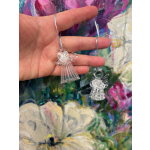 Two clear angel ornaments held in a hand against a floral background