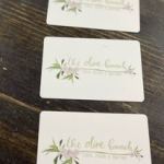 Three white cards with faint floral designs on a dark wood surface