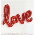 Red foil balloons spelling "love" on a white wall