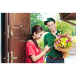 Man holding a colorful bouquet while a woman checks her phone at the door
