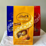 Three Lindt Lindor chocolate gift bags in blue, yellow, and red