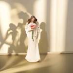 White angel figurine holding a small pink flower bouquet