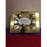 Box of Ferrero Rocher hazelnut chocolates in gold packaging on a purple and red surface