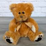 Brown teddy bear with a ribbon bow sitting on a gray surface