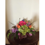 Colorful mixed flower arrangement in a clear glass vase on a table