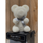 Pearl-covered teddy bear with a gray ribbon on a black box