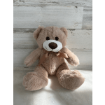 Plush teddy bear with a ribbon bow sitting against a wood backdrop