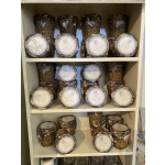 Shelf of wicker candle jars with round labeled lids