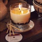 Lit soy candle in a glass tumbler on a saucer with matches nearby