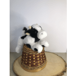 Black-and-white plush cow sitting in a woven basket